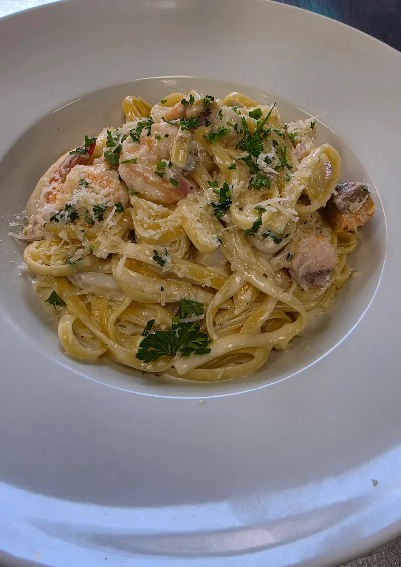 Medium hot sausage and shrimp pasta with onions, spinach and tomato.